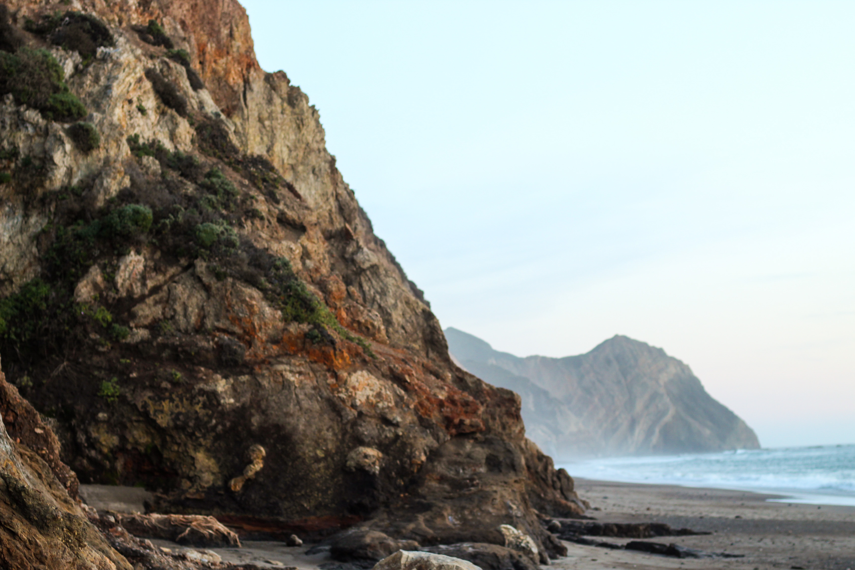 A weathered coastal cliff with a distant headland and beach